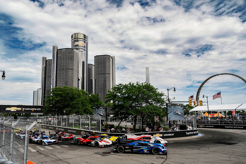 Indycars making turn during Detroit Street Circuit with downtown Detroit in the background